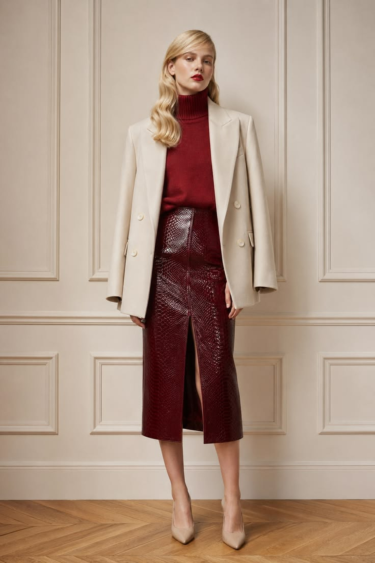 Cream double-breasted blazer layered over a burgundy turtleneck and textured burgundy midi skirt with neutral pumps.